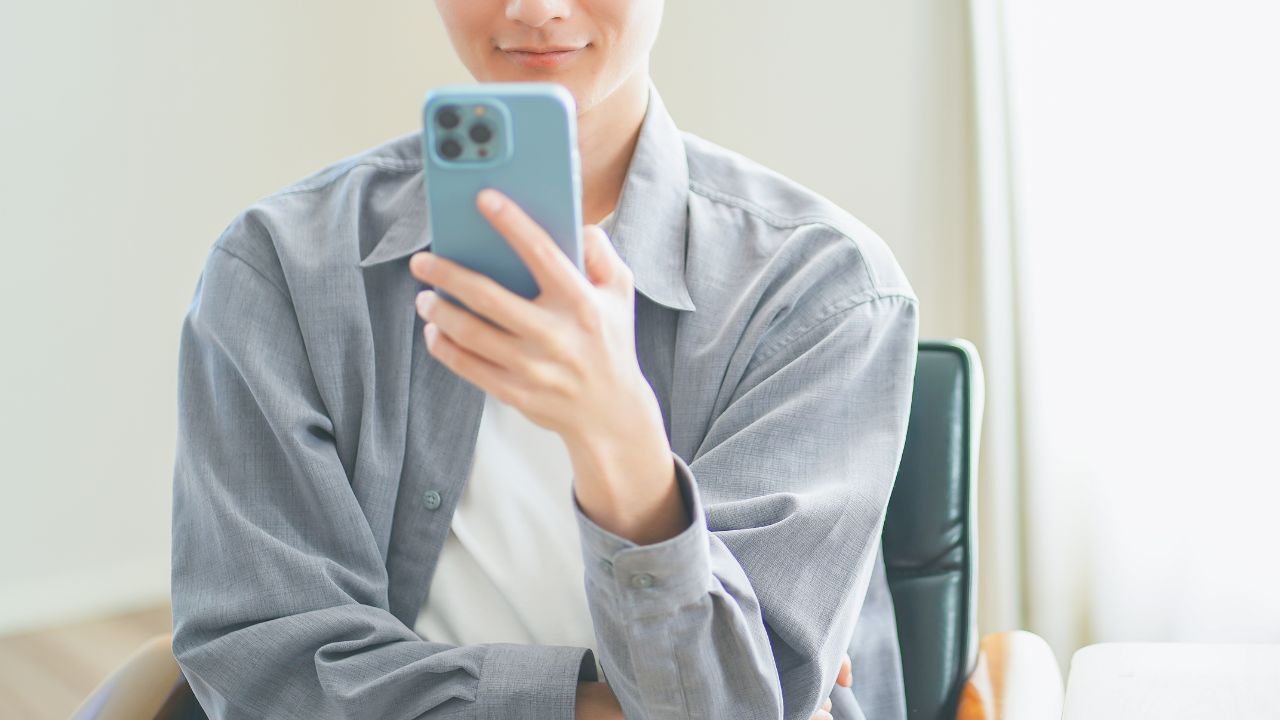 スマホ操作している男性の画像